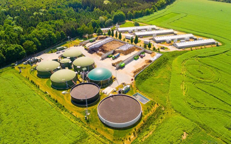 Aerial view over biogas plant and farm in green fields