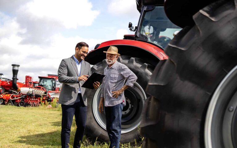 Two people discussing loans in front of tractors